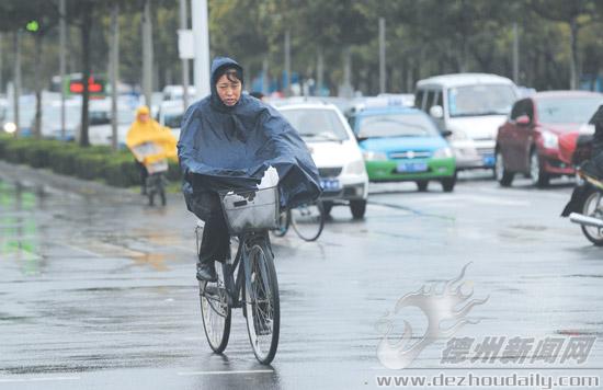 10月14日，市民在市區(qū)東方紅路雨中騎行。